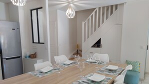 A modern kitchen with a wooden dining table set for four, white chairs, and a staircase leading to another level. - 3 bedroom house in La Môle, Gulf of Saint Tropez in residence with swimming pool (La Mole)