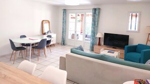 A living room with a dining area, a TV, and a sofa. - 3 bedroom house in La Môle, Gulf of Saint Tropez in residence with swimming pool (La Mole)
