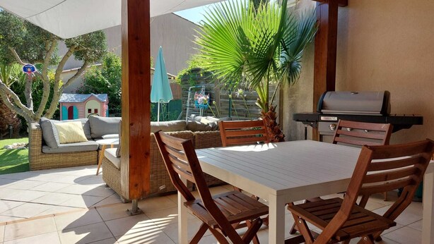 An outdoor patio with a table and chairs, a grill, a small playhouse, and a palm tree. - 3 bedroom house in La Môle, Gulf of Saint Tropez in residence with swimming pool (La Mole)