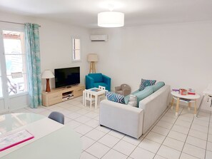 Uma sala de estar moderna com sofá, TV e uma mesinha.