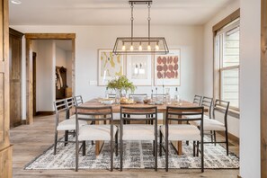 Ein Esszimmer mit einem Holztisch, sechs Stühlen, einer Chandelüster und Bildern an den Wänden.