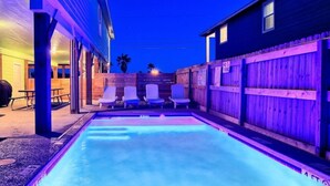 A swimming pool with lounge chairs and a wooden fence. - Crustacean Station- Private Pool - Cart Discount (Port Aransas)