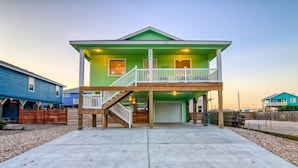 A two-story house with a front porch and a garage. - Crustacean Station- Private Pool - Cart Discount (Port Aransas)