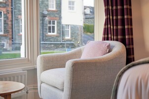 A room with a grey armchair by a window with a view of a building.