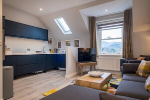 A modern kitchen with dark cabinets, a central island, and a large window with curtains.
