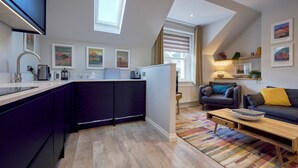 Una cocina moderna con una isla central, un área de comedor con sofá y mesa de centro, y una sala de estar con chimenea.