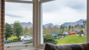 A room with a large window offering a view of a parking area and mountains. - Howe Keld 5 First Floor (Keswick)