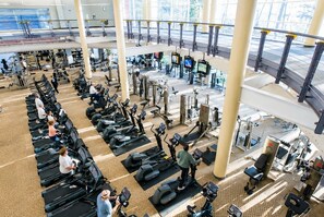 A multi-level gym with various exercise equipment, including treadmills, ellipticals, and weight machines.