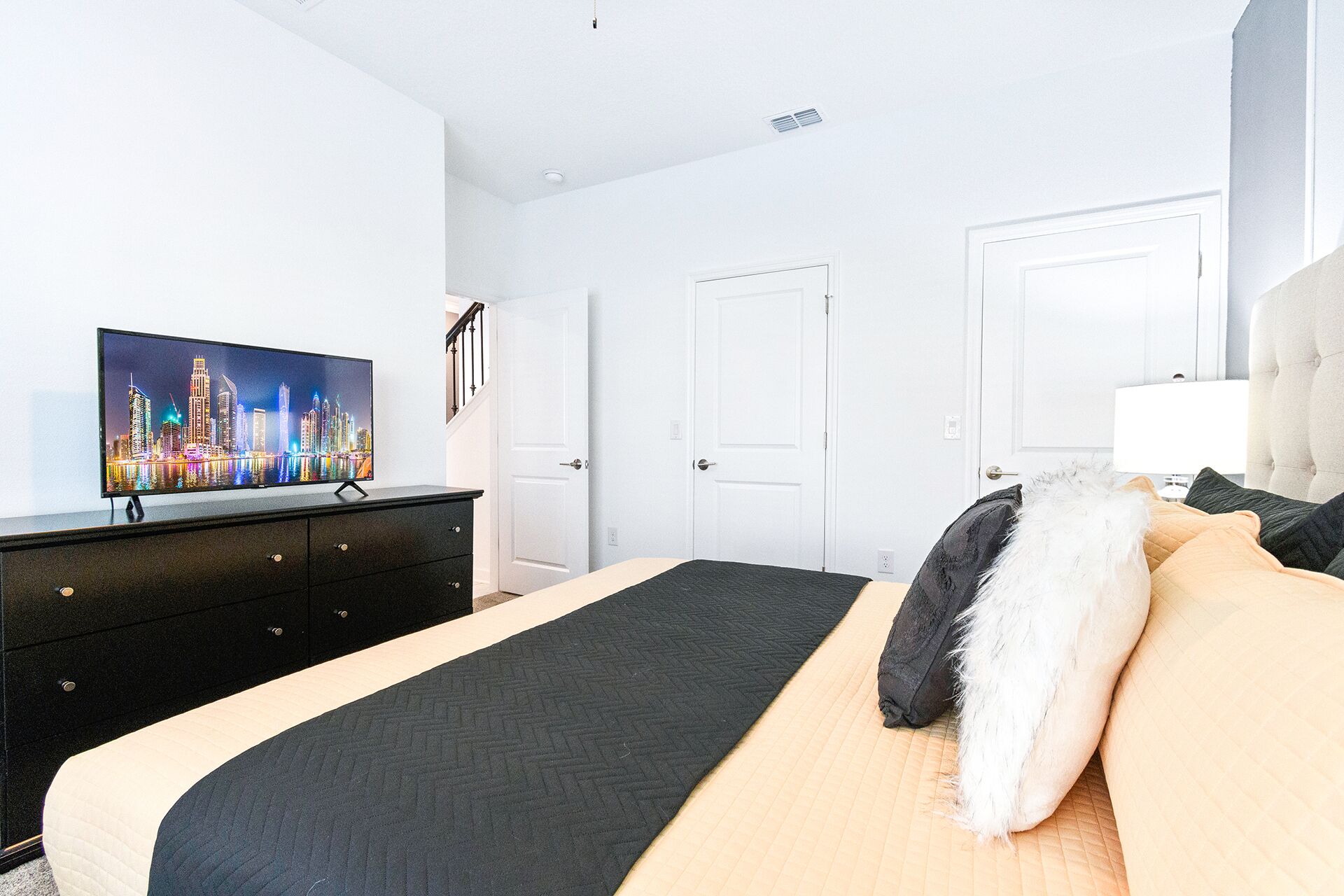 Une chambre d’hôtel avec un lit, un téléviseur posé sur une commode et deux portes.