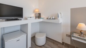 A modern bathroom with a white sink, toilet, and shower area. There is a television mounted on the wall and a small table with a lamp and toiletries. - Panoramic Studio Carloforte (Carloforte)