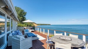 Una terraza con mobiliario de mimbre, una mesa y vistas al mar.
