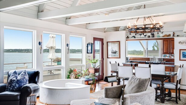 Amplia sala de estar con vista al agua, una mesa de comedor y una cocina con armarios de madera.