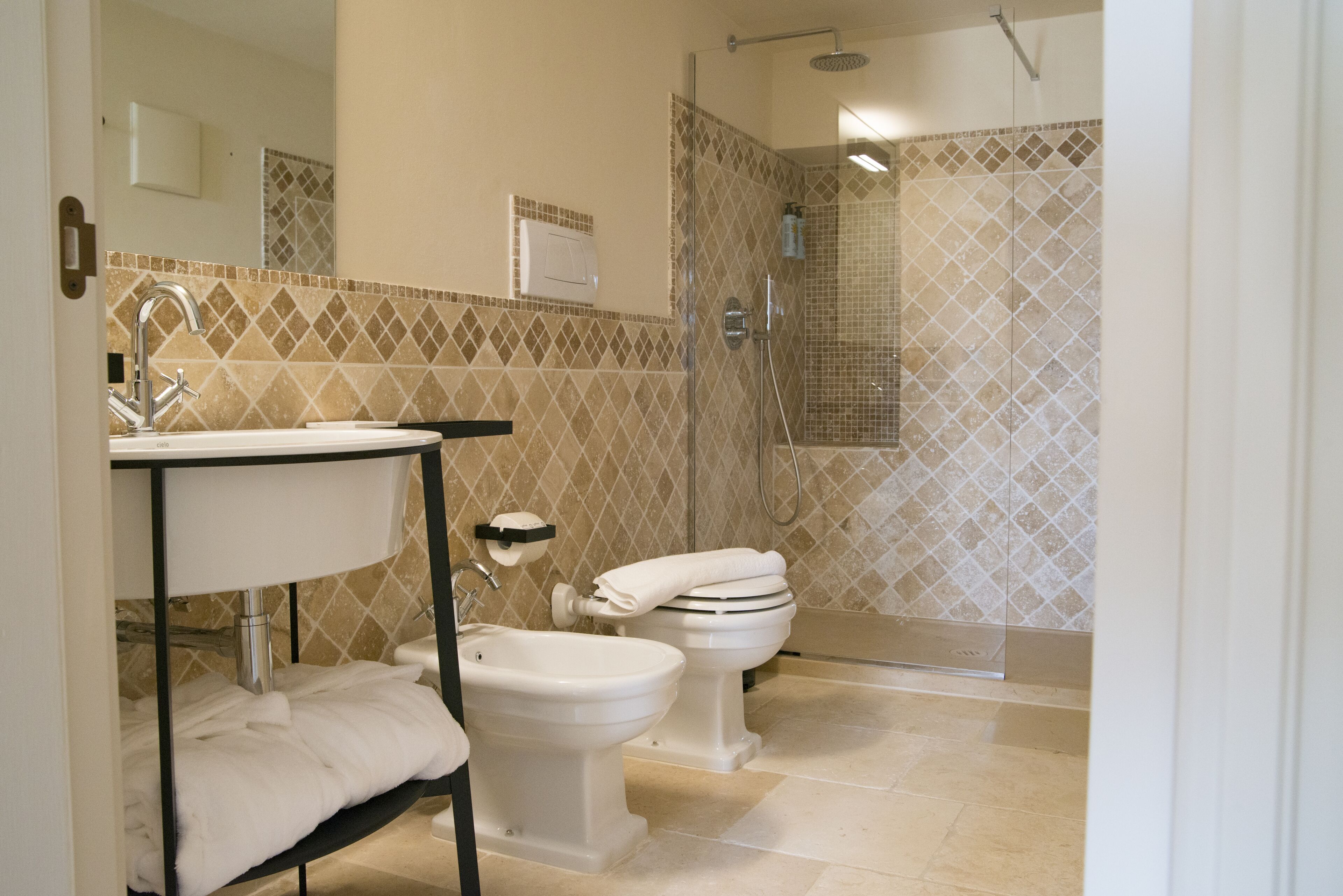 A bathroom with a sink, bidet, toilet, and a shower area.