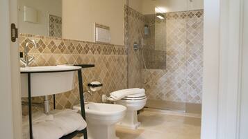 A bathroom with a sink, bidet, toilet, and a shower area.