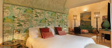 A spacious bedroom with a large bed, a small round table, and a green sofa.