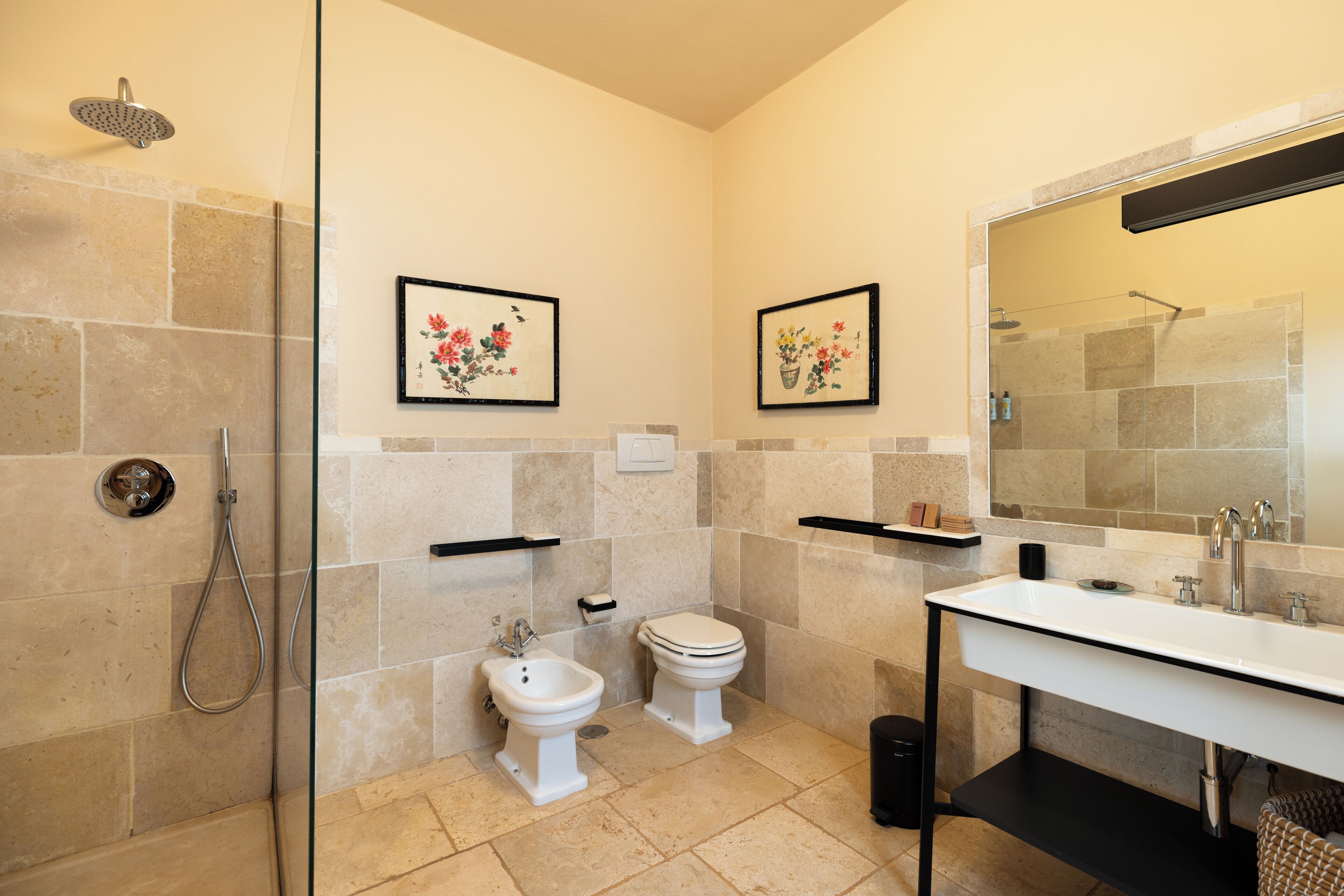 Un baño con ducha, bidé, inodoro y un espejo grande.