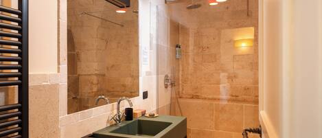 A modern bathroom with a rectangular sink, a glass-enclosed shower, and a large mirror.