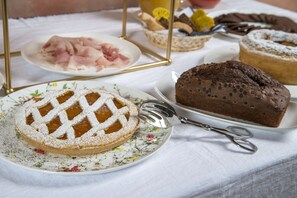 A table with various food items including a lattice-topped pie, a chocolate cake, and a plate of sliced meats. - Masseria Santo Scalone (Ostuni)
