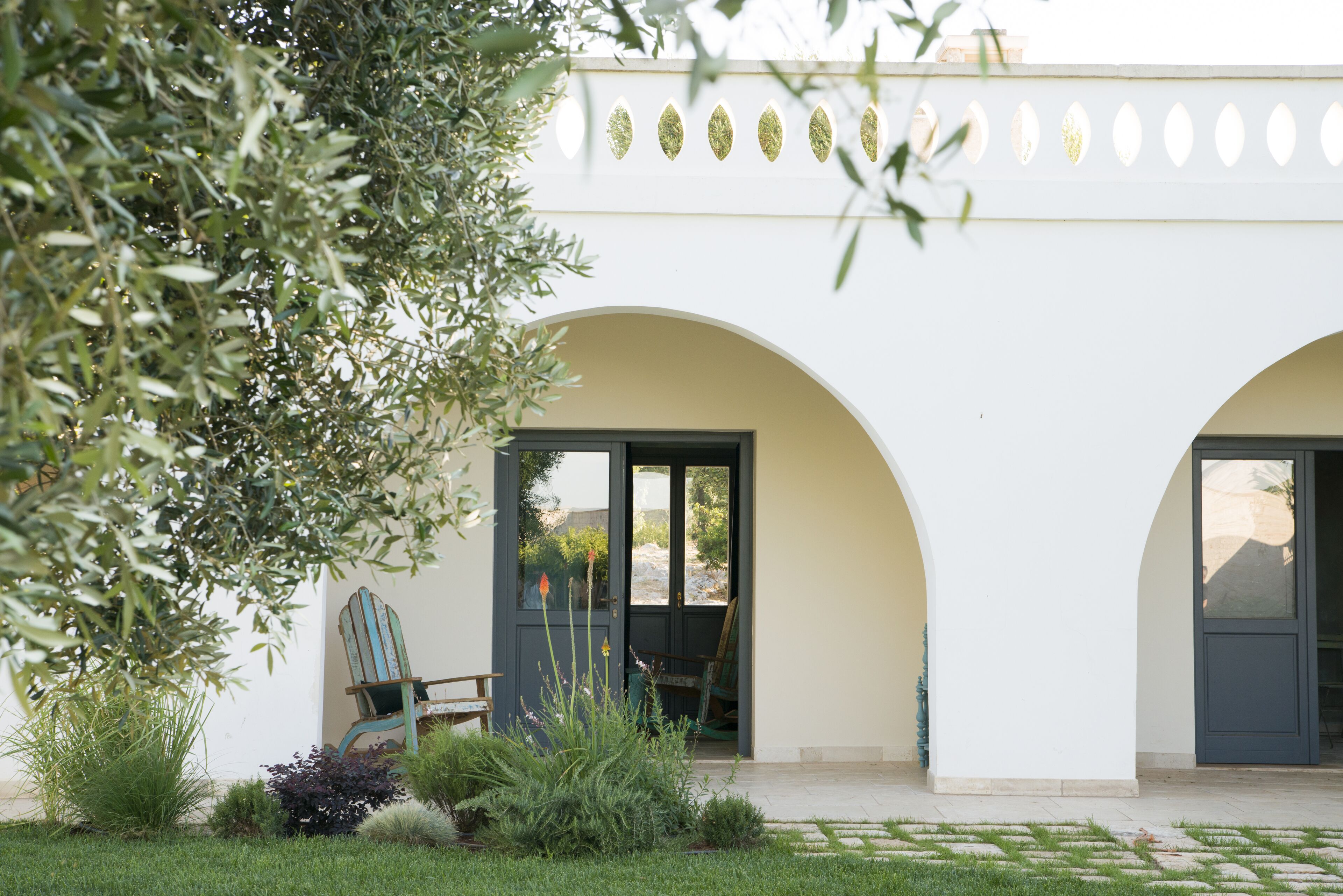 A building with two arched doorways, a bench, and a chair outside.