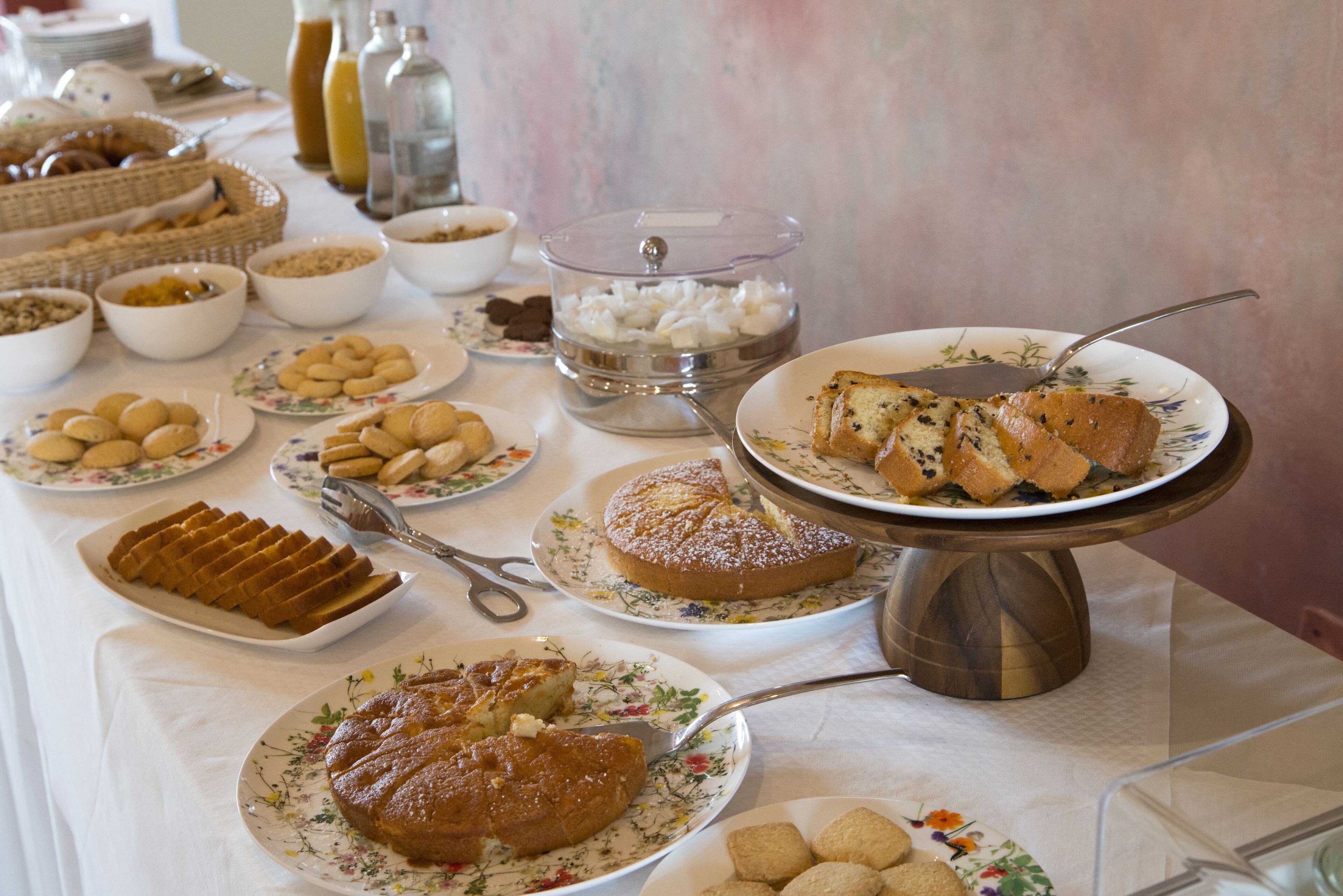 Una mesa de buffet con diversos platos, incluyendo pasteles, repostería y una variedad de postres.