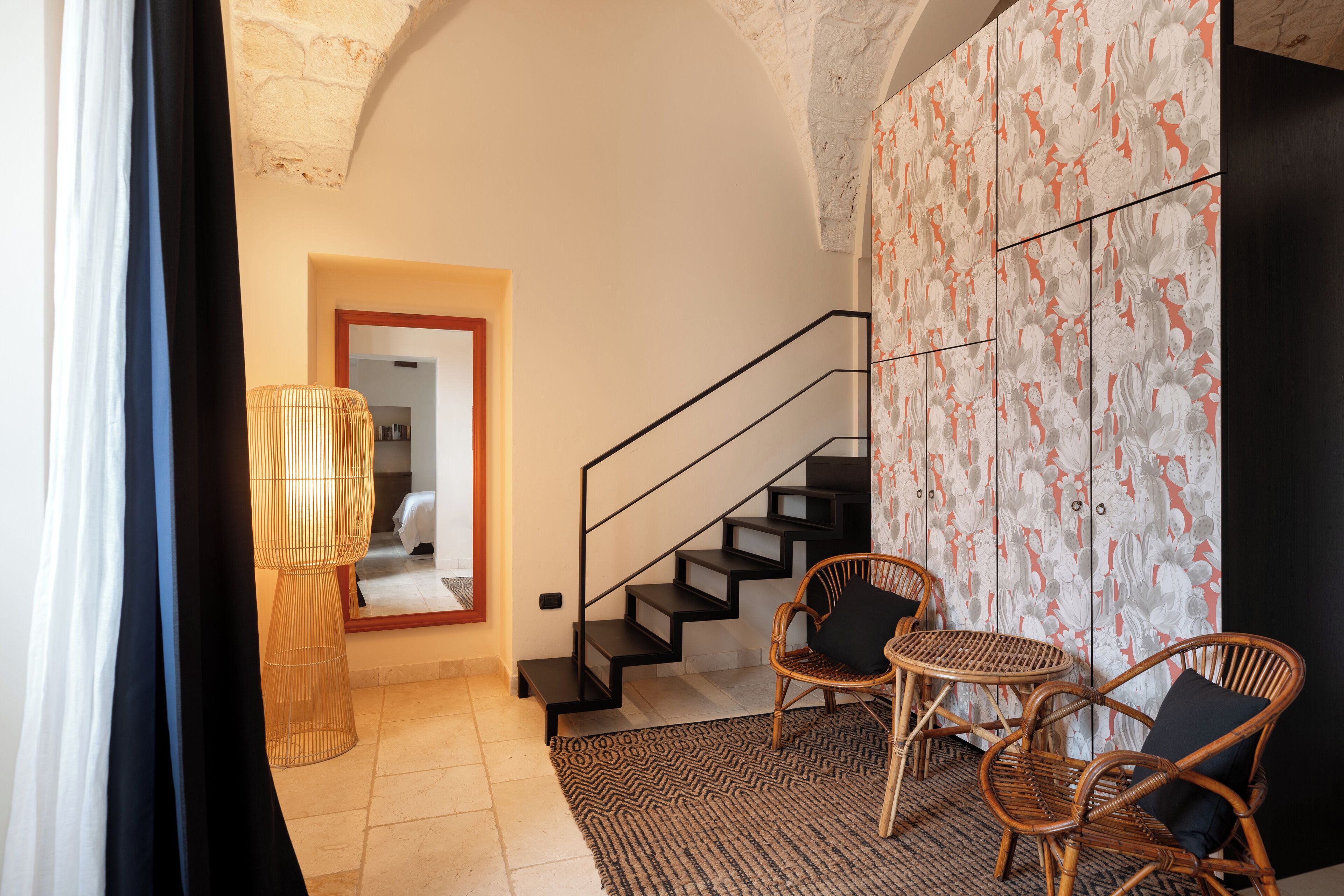 A modern interior with a staircase, wicker chairs, a patterned wall, and a textured ceiling.