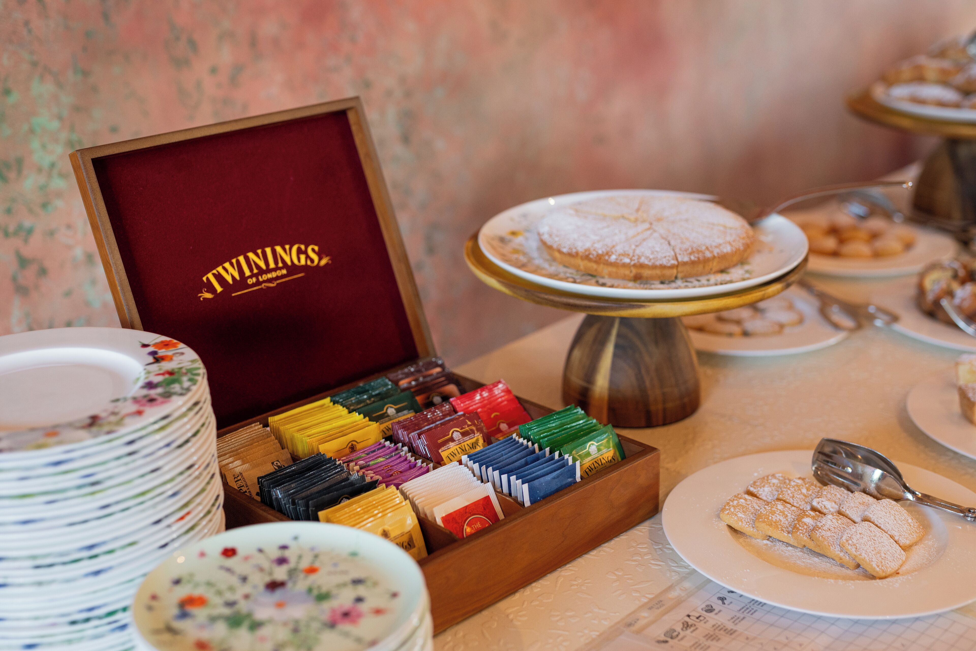 Un bufé de postres con diversos dulces y una caja con la etiqueta "TWININGS OF LONDON".