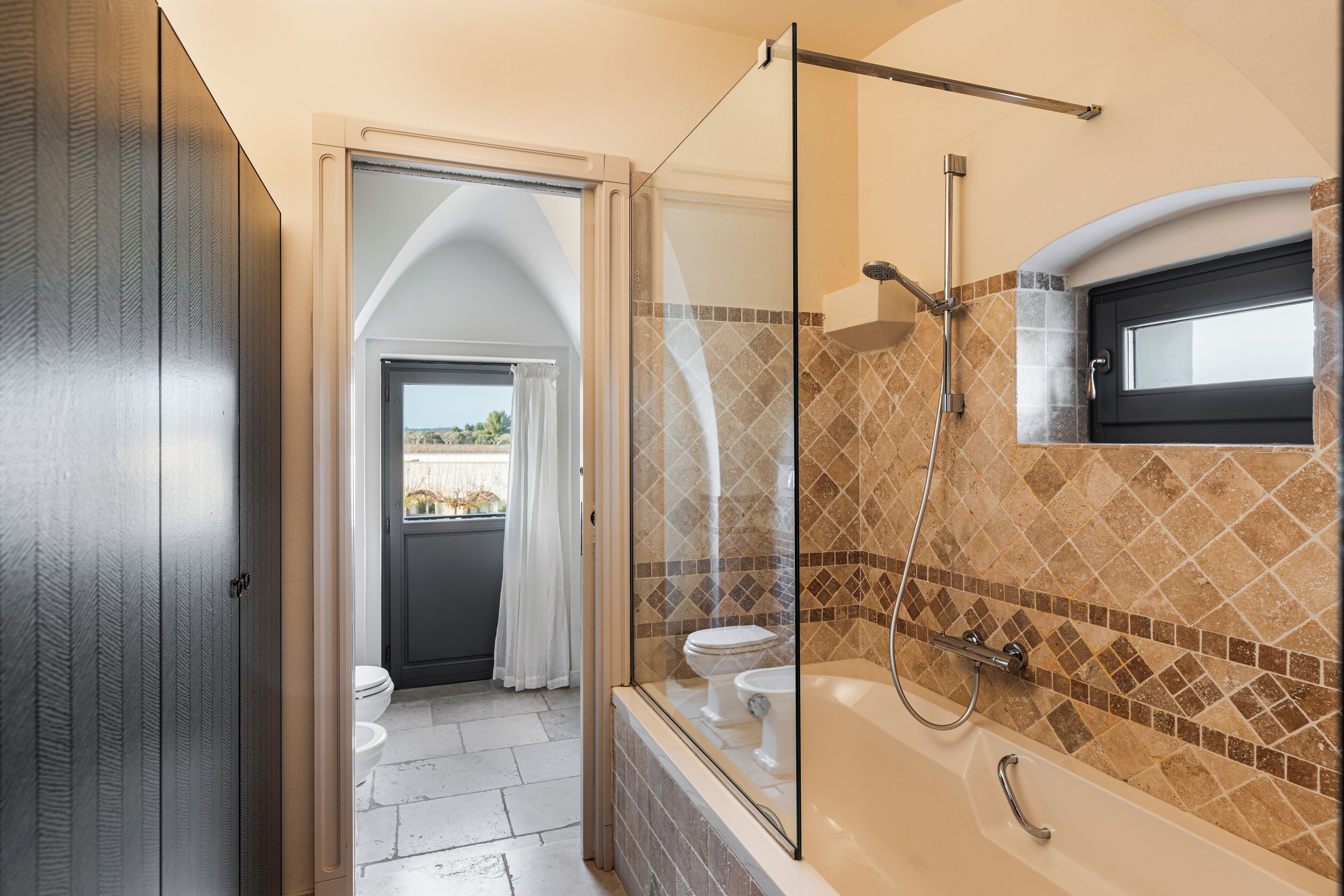 A modern bathroom with a glass-enclosed shower, a bathtub, and a toilet.
