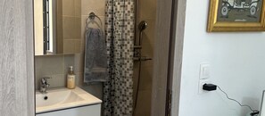 A bathroom with a sink, a towel rack, a shower curtain, and a power outlet.