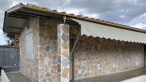 A building with a stone facade, a covered patio, and a metal roof. - Ecological Studio Flat in Kalyvia Thorikou, Greece (Saronikos)