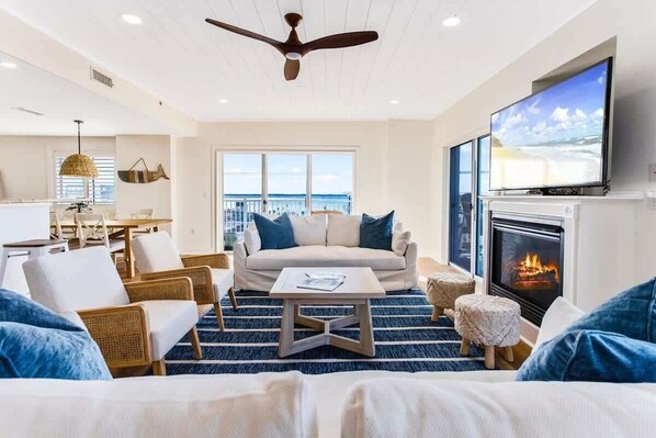 A modern living room with a sofa, chairs, a coffee table, a fireplace, and a TV.