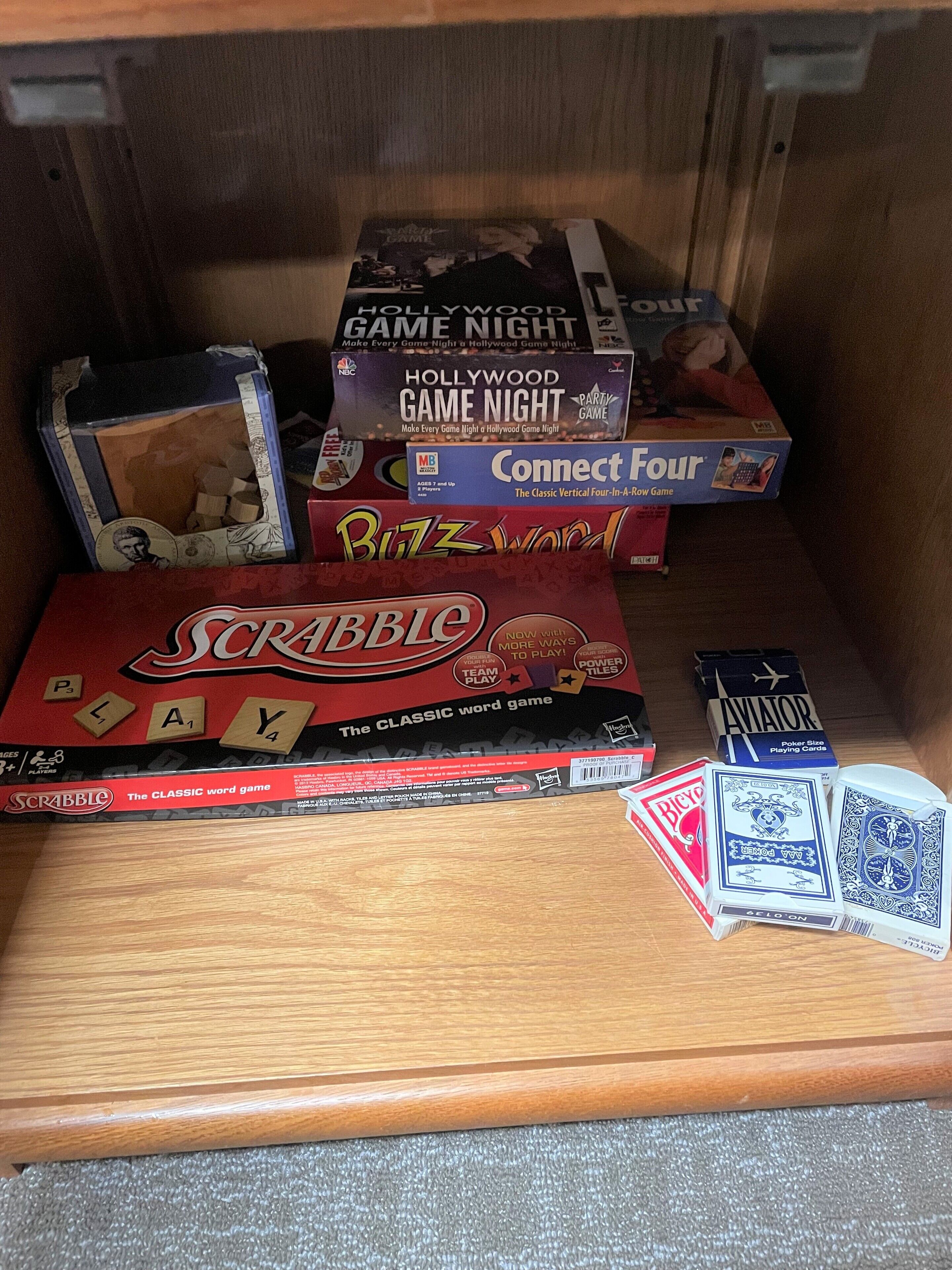 Ein Holzregal mit verschiedenen Gesellschaftsspielen und Spielkarten.