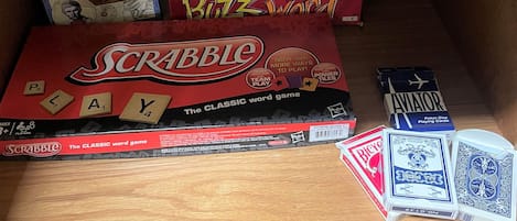 Ein Holzregal mit verschiedenen Gesellschaftsspielen und Spielkarten.