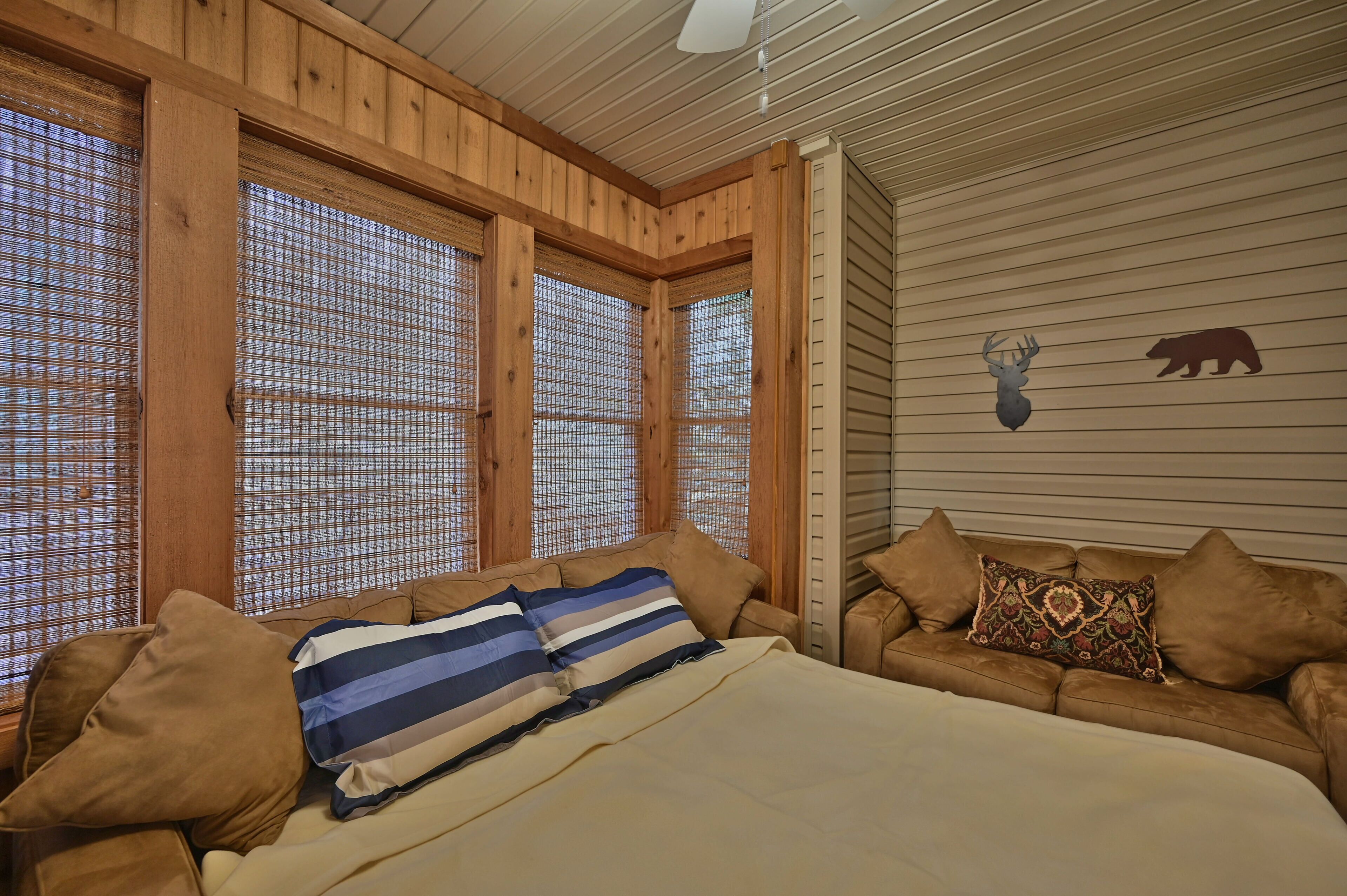 Een gezellige kamer met een bed, een slaapbank en een herten decoratie aan de muur.