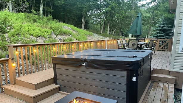 Un bain à remous sur une terrasse en bois, avec un foyer à proximité.