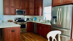 A kitchen with wooden cabinets, stainless steel appliances, a microwave, a stove, and a refrigerator.