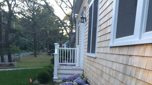 A house with a front yard featuring a flower bed with purple hydrangeas.
