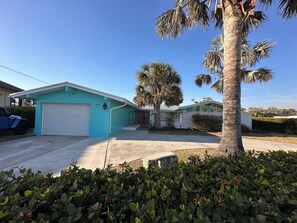 A residential property with a garage, a palm tree, and a well-maintained lawn.