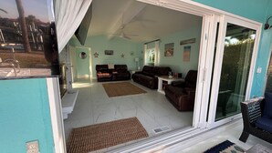 A spacious living area with a sliding glass door leading to a balcony, a ceiling fan, and a dining area with a table and chairs.