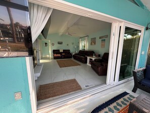 A spacious living area with a sliding glass door, a ceiling fan, and a dining table. - Waterfront 3‑bedroom home with heated pool on a deep sailboat‑access canal. Features EV charging, garage, and stocked kitchen. Near Downtown Punta Gorda, Fisherman’s Village, Isle Yacht Club, and PGD airport. (Punta Gorda)