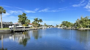 A calm waterway with boats docked on the left, surrounded by trees and buildings.