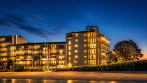 A multi-story hotel with balconies, a water body in front, and a clear sky. - Beautiful apartment directly on the beach Living room and terrace with panoramic sea view     (Heiligenhafen)
