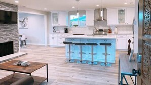 A modern kitchen with white cabinets, a central island with bar stools, a built-in oven, and a large window. - Prime Location: Lux 4BR w Pool/Spa/Cabana/Firepit (San Diego)