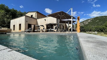 Una piscina al aire libre de temporada, sombrillas