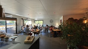A restaurant with a casual dining layout, featuring tables and chairs arranged for groups. - Le Volcans des Sens (Torsiac)