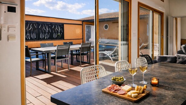 A modern kitchen with a dining area, a view of the outdoors, and a table set with food and drinks. - Family villa with pool – 6 guests (Les Sables-d´Olonne)