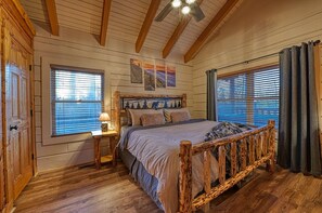 A cozy bedroom with a wooden bed, a nightstand, and a ceiling fan.