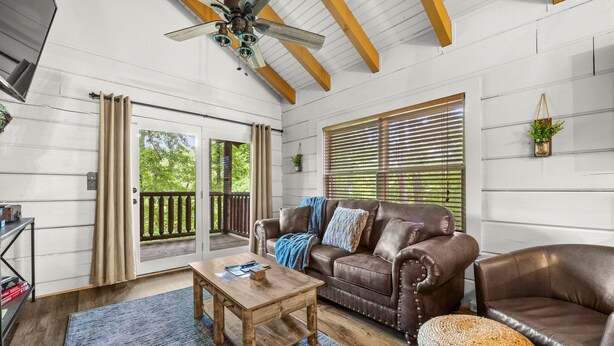 A cozy living room with a brown leather sofa, a wooden coffee table, and a ceiling fan. - Rustic Retreat in the Smokies (Sevierville)