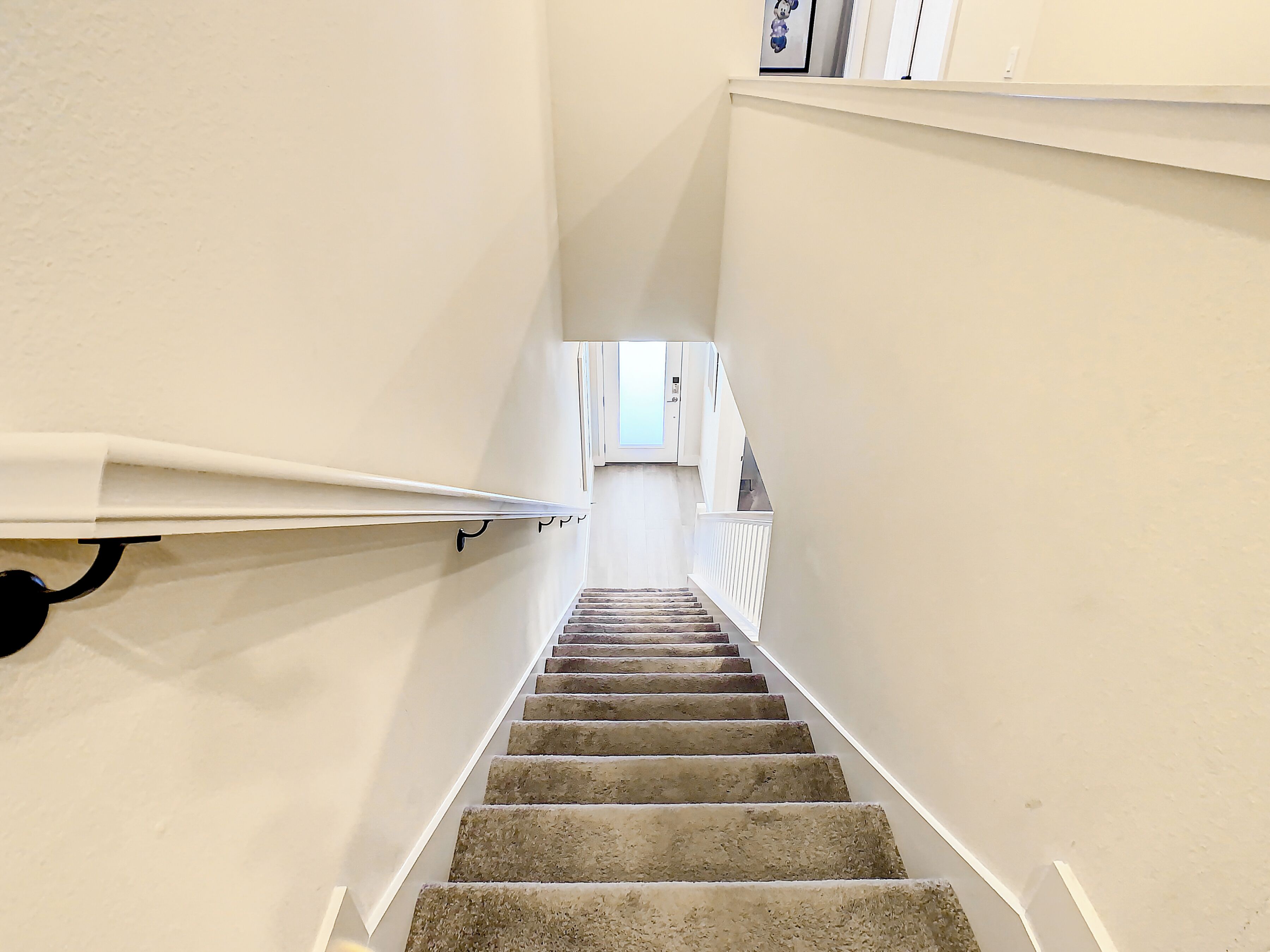 Una escalera con peldaños alfombrados que conduce a un rellano con una ventana y una puerta.
