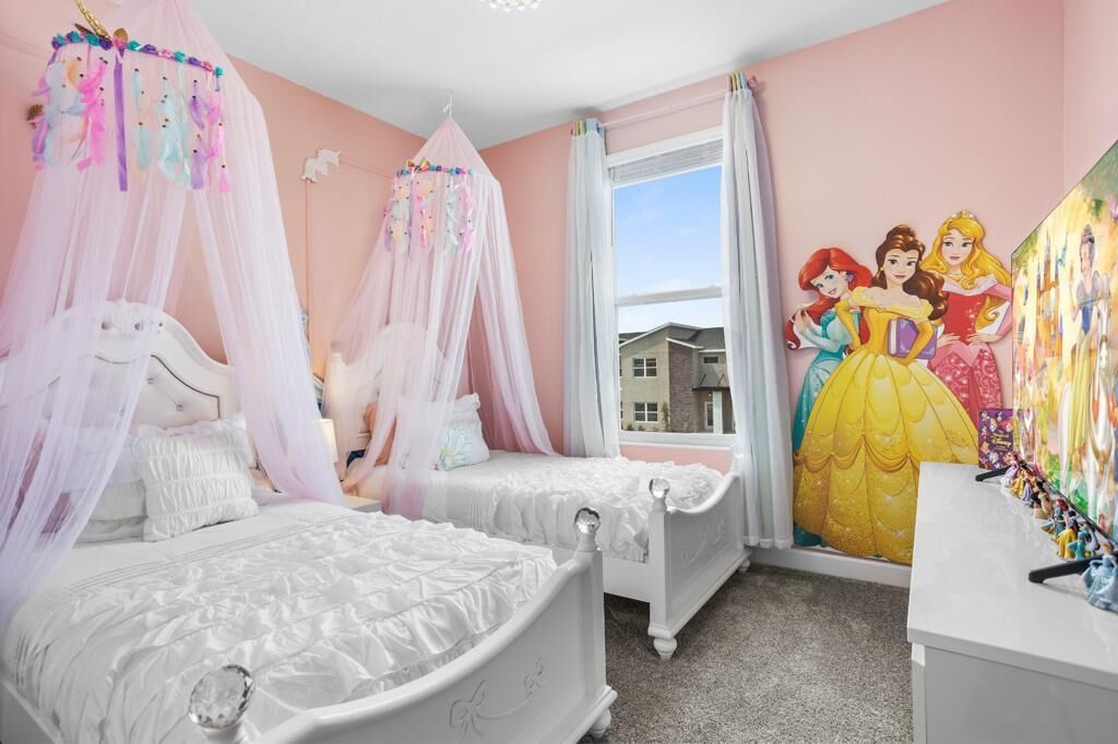 A bedroom with two beds, a window with curtains, and a wall mural of princesses.