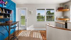 A modern interior with a blue accent wall, a wooden staircase, a door with a bull skull decoration, and a window with blinds. - 1- King bed/ 1- sofa bed/ 1.5bath Block from Beach (Cocoa Beach)